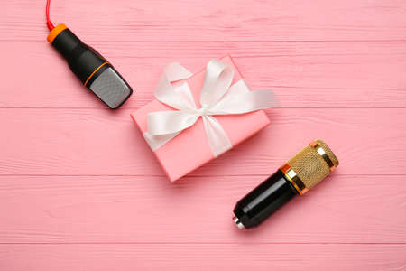 Modern microphones and gift on color wooden backgroundの写真素材