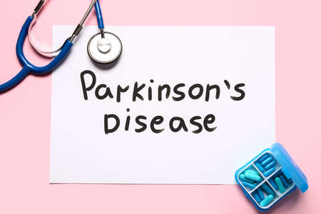 Paper sheet with text PARKINSON'S DISEASE, stethoscope and pills on pink backgroundの写真素材