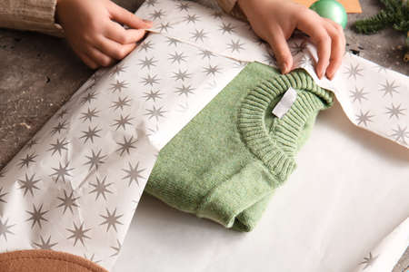 Woman making beautiful Christmas gift on table, closeup