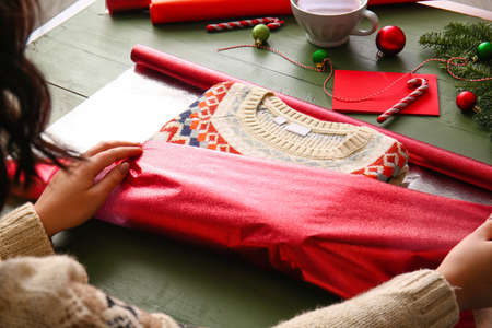 Woman making stylish Christmas gift on color wooden tableの写真素材