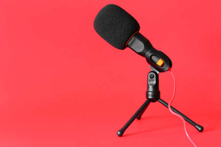 Stand with modern microphone on red backgroundの写真素材