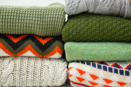 Stacks of stylish sweaters, closeup