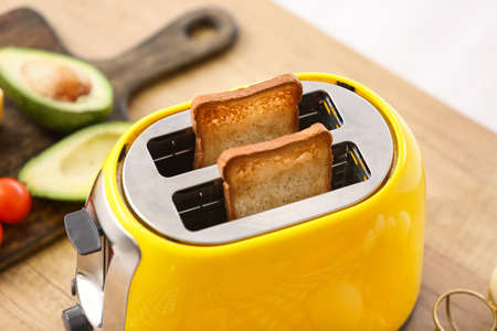 Yellow toaster with bread slices in kitchen, closeupの写真素材