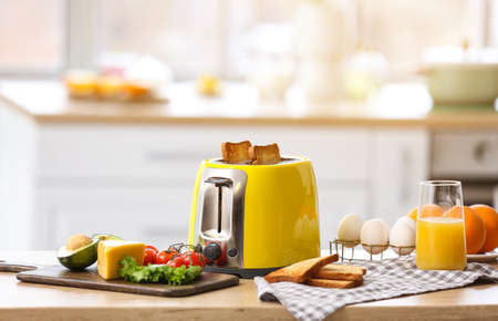 Yellow toaster with healthy food on table in light kitchenの写真素材