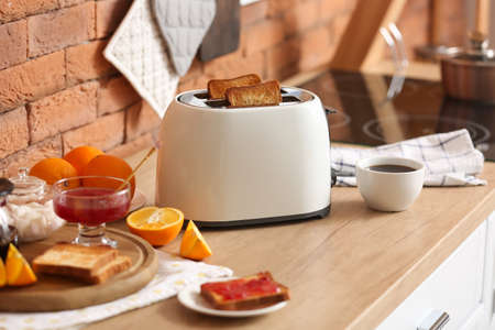 White toaster with tasty breakfast on counter near brick wall