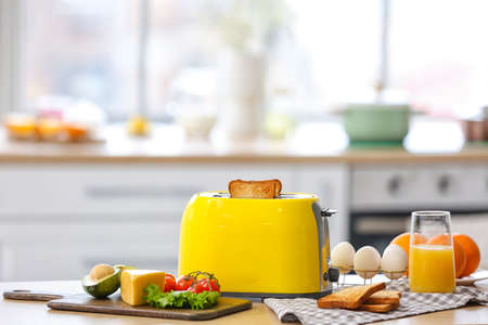 Yellow toaster with healthy food on table in light kitchenの写真素材