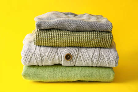 Stack of stylish sweaters on yellow backgroundの写真素材