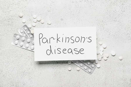 Paper sheet with text PARKINSON'S DISEASE and pills on grunge backgroundの写真素材