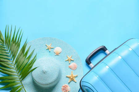 Suitcase, straw hat, palm leaf and seashells on blue backgroundの写真素材