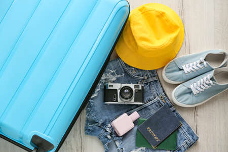 Blue suitcase, clothes female and traveler accessories on light wooden floorの写真素材