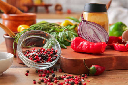 Bowl with peppercorns and vegetables on table