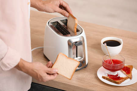 Young man making tasty toasts in kitchen, closeup