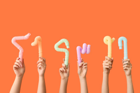 Hands with popular pop tubes on color background