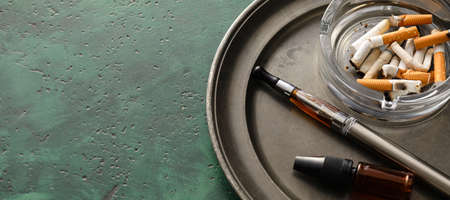 Tray with set for smoking and cigarette butts on green background with space for text