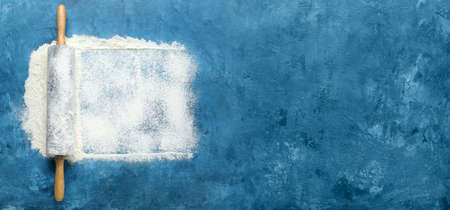 Fresh flour and rolling pin on blue background with space for textの写真素材