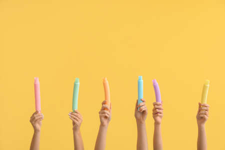 Hands with popular pop tubes on color background