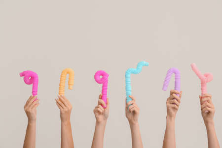 Hands with popular pop tubes on light backgroundの写真素材
