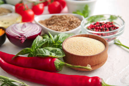 Bowls with spices, basil and vegetables on light background, closeupの写真素材