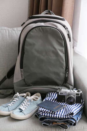 Backpack, female clothes, passport and photo camera on sofaの写真素材