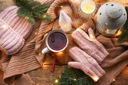 Warm gloves, scarf, hat, cup of tea and lantern on wooden backgroundの写真素材