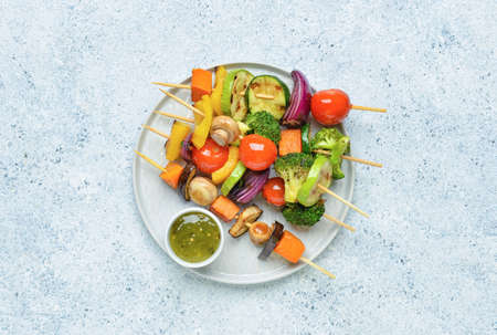 Plate with tasty vegetable skewers and sauce on light backgroundの写真素材