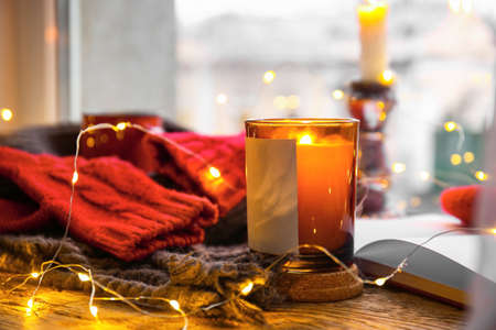 Burning candle and Christmas lights on windowsill