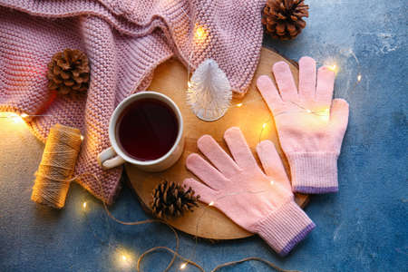 Warm gloves, cup of tea and Christmas lights on blue backgroundの写真素材