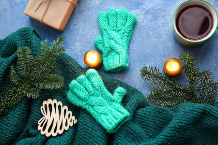 Warm gloves, cup of tea and burning candles on blue backgroundの写真素材
