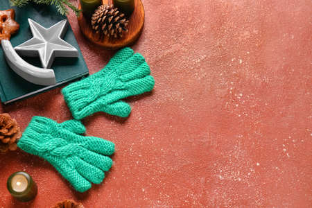 Warm gloves, burning candle, book and Christmas decor on red backgroundの写真素材