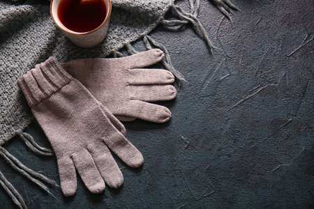 Warm gloves and cup of tea on black backgroundの写真素材