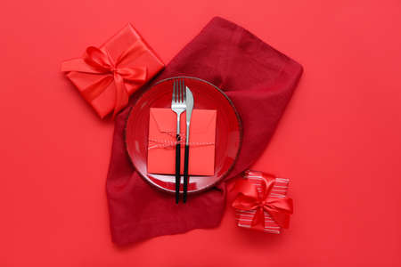Stylish table setting and gifts for Valentine's Day on red backgroundの写真素材