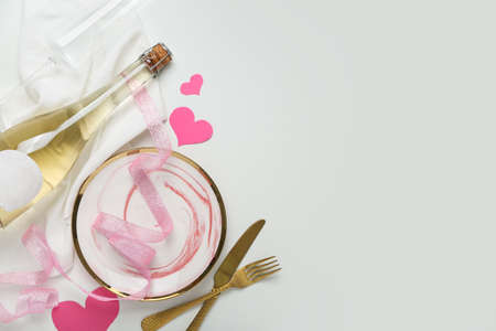 Stylish table setting for Valentine's Day and bottle of champagne on light backgroundの写真素材