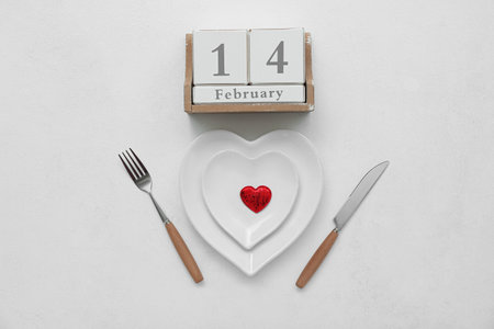 Stylish table setting for Valentine's Day and calendar on light background