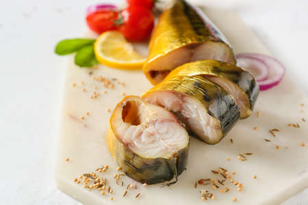 Board with cut smoked mackerel fish on light background, closeup