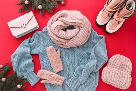 Stylish winter clothes, accessories, shoes and Christmas decor on red backgroundの写真素材