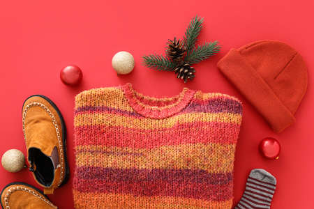 Stylish winter clothes, shoes and winter decor on red backgroundの写真素材