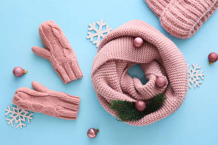 Beautiful composition with knitted hat, scarf, mittens and Christmas decor on blue backgroundの写真素材