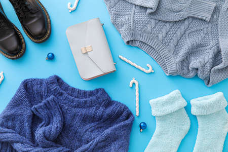 Warm clothes, shoes, bag and winter decor on blue backgroundの写真素材