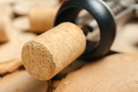 Wine cork and opener on wooden background, closeup