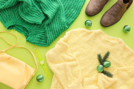 Warm sweaters, shoes, bag and Christmas decor on green background