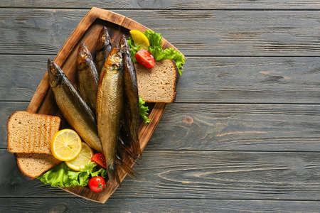 Board with smoked herring fishes and bread on dark wooden backgroundの写真素材