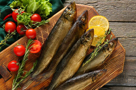 Board with smoked herring fishes on table, closeup