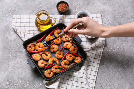 Woman eating tasty shrimp tails on gray backgroundの写真素材