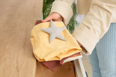 Woman holding baby clothes near chest of drawers in children's roomの写真素材
