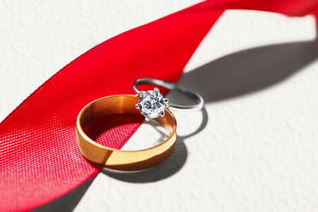Beautiful rings with red ribbon on light background, closeupの写真素材