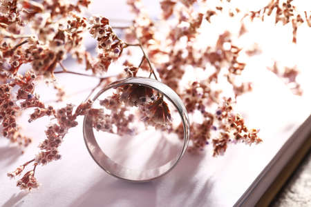 Beautiful silver engagement ring with flowers on book, closeupの写真素材