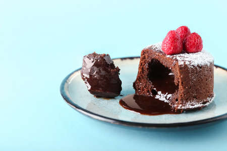 Plate with tasty lava cake fondant and raspberry on blue background, closeup