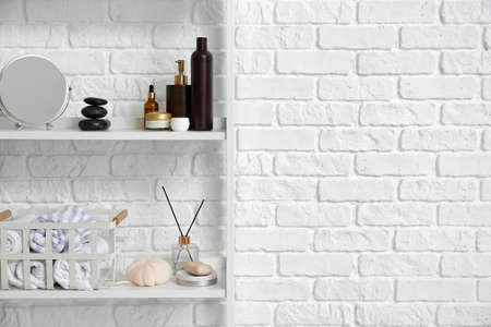 Shelving unit with bath supplies near white brick wallの写真素材