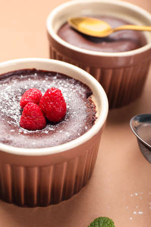 Ramekin with tasty lava cake fondant and raspberry on color background, closeup