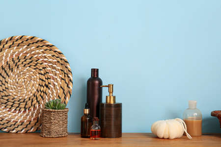Bath accessories and flower pot on wooden bench near blue wallの写真素材